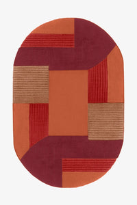 Oval hand-tufted wool rug in red, burgundy, and orange blocks, perfect for bold modern interiors