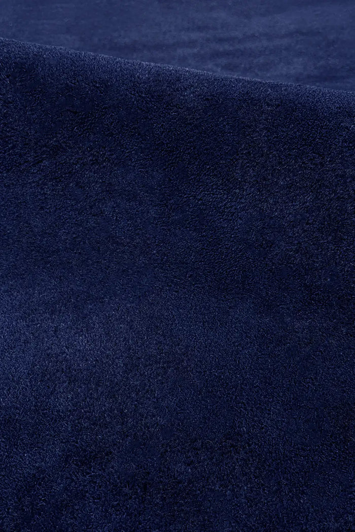 Close-up of navy blue wool rug surface showing plush tufted pile and rich deep color saturation