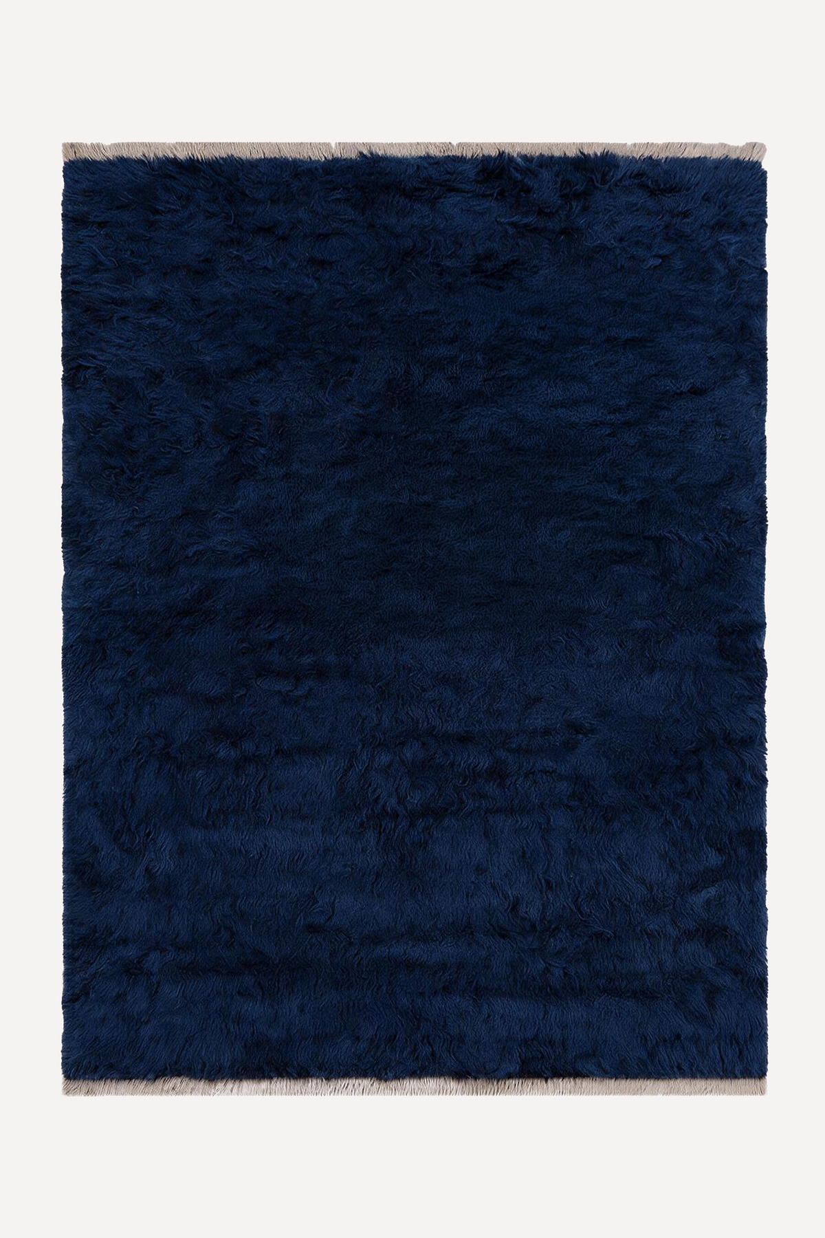 A dark navy blue shaggy area rug with light beige fringe on the top and bottom edges, shown flat against a light off-white background.