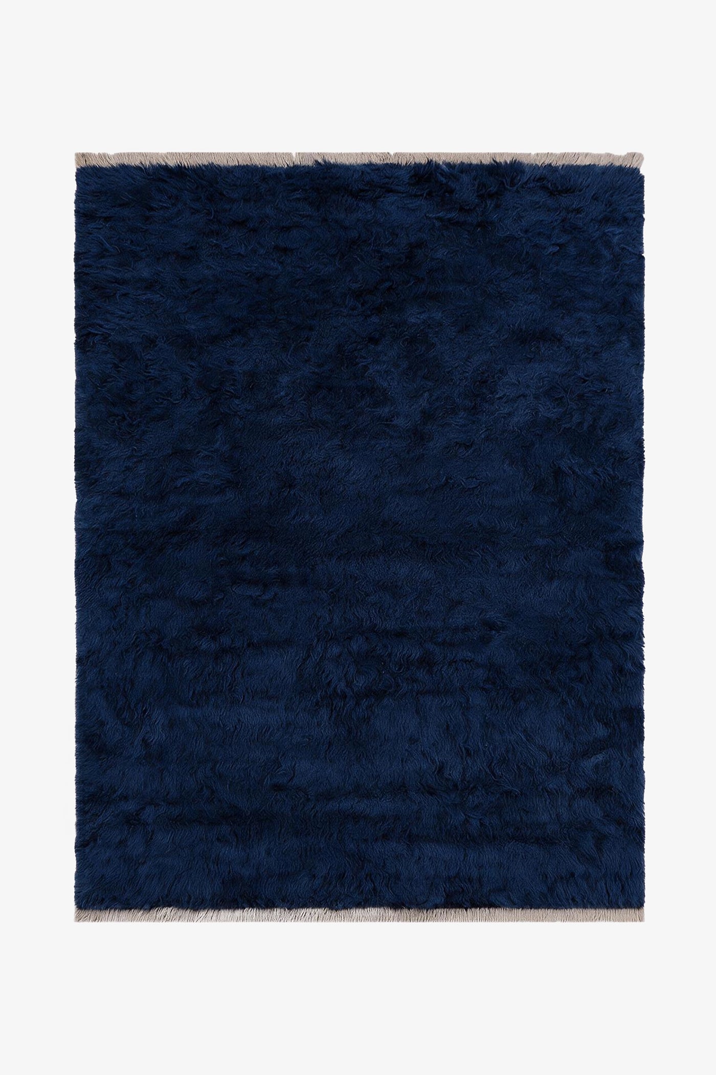 A dark navy blue shaggy area rug with light beige fringe on the top and bottom edges, shown flat against a white background.