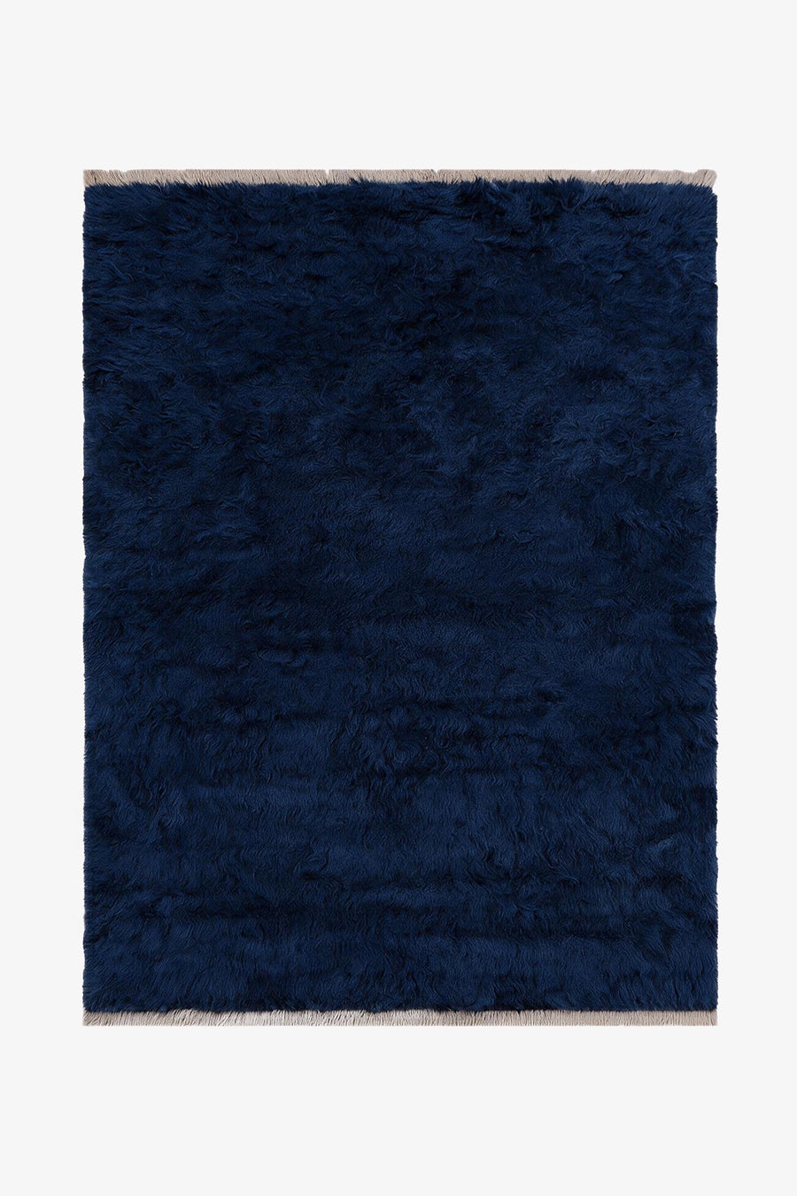A dark navy blue shaggy area rug with light beige fringe on the top and bottom edges, shown flat against a white background.