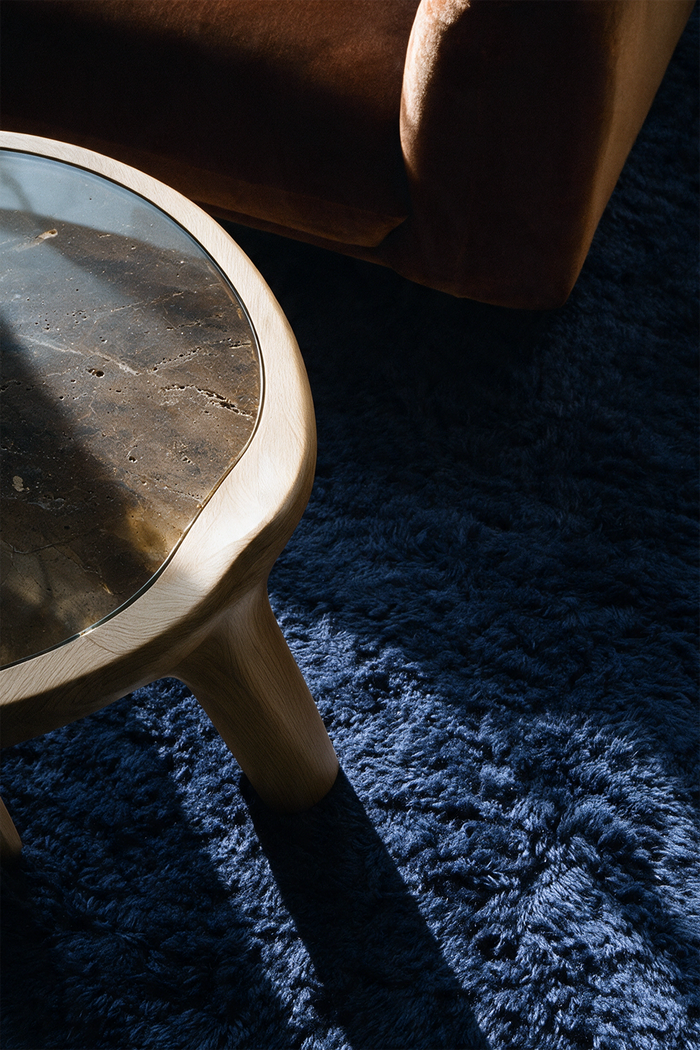 navy shag wool rug beneath a brass and stone side table and a brown velvet sofa lifestyle
