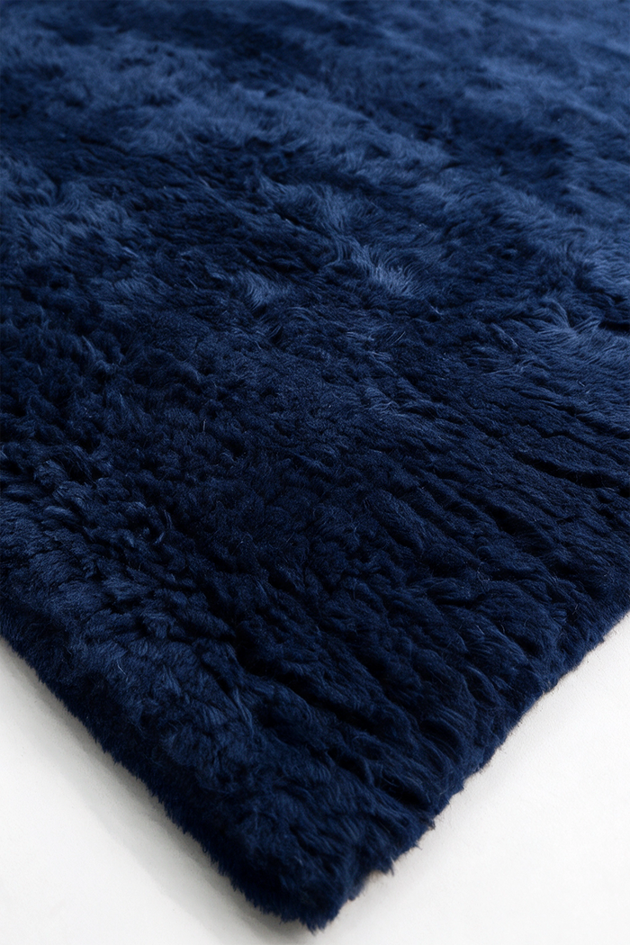 close up texture of a navy hand-knotted shag wool rug with a deep soft pile