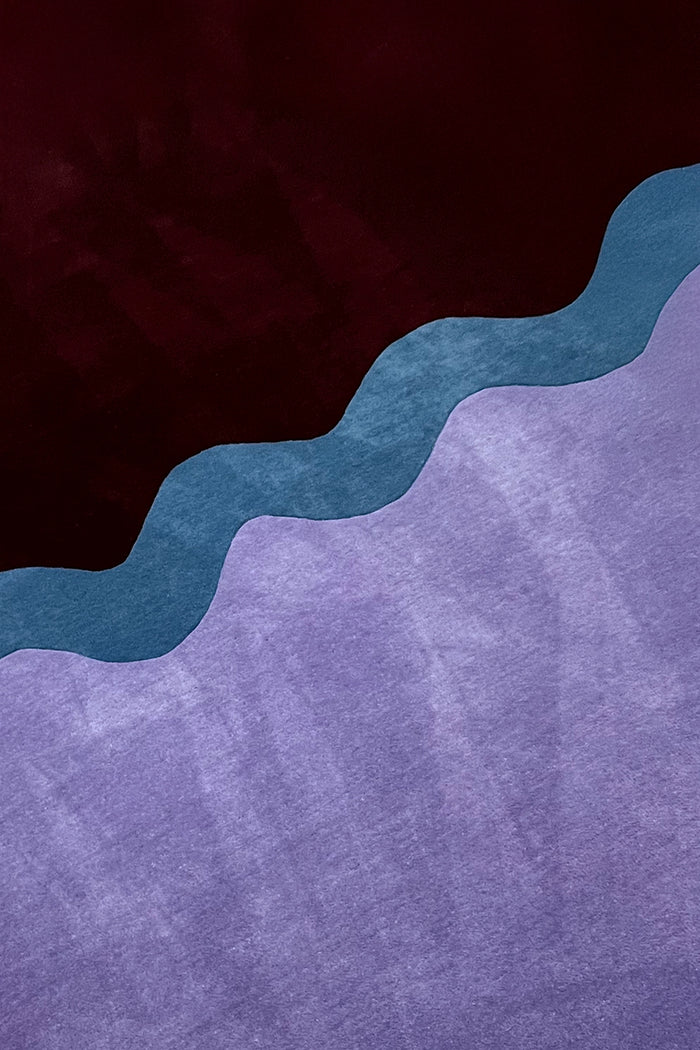 close up of the neapolitan hand-tufted wool rug pattern showing a wavy teal band between purple and dark brown