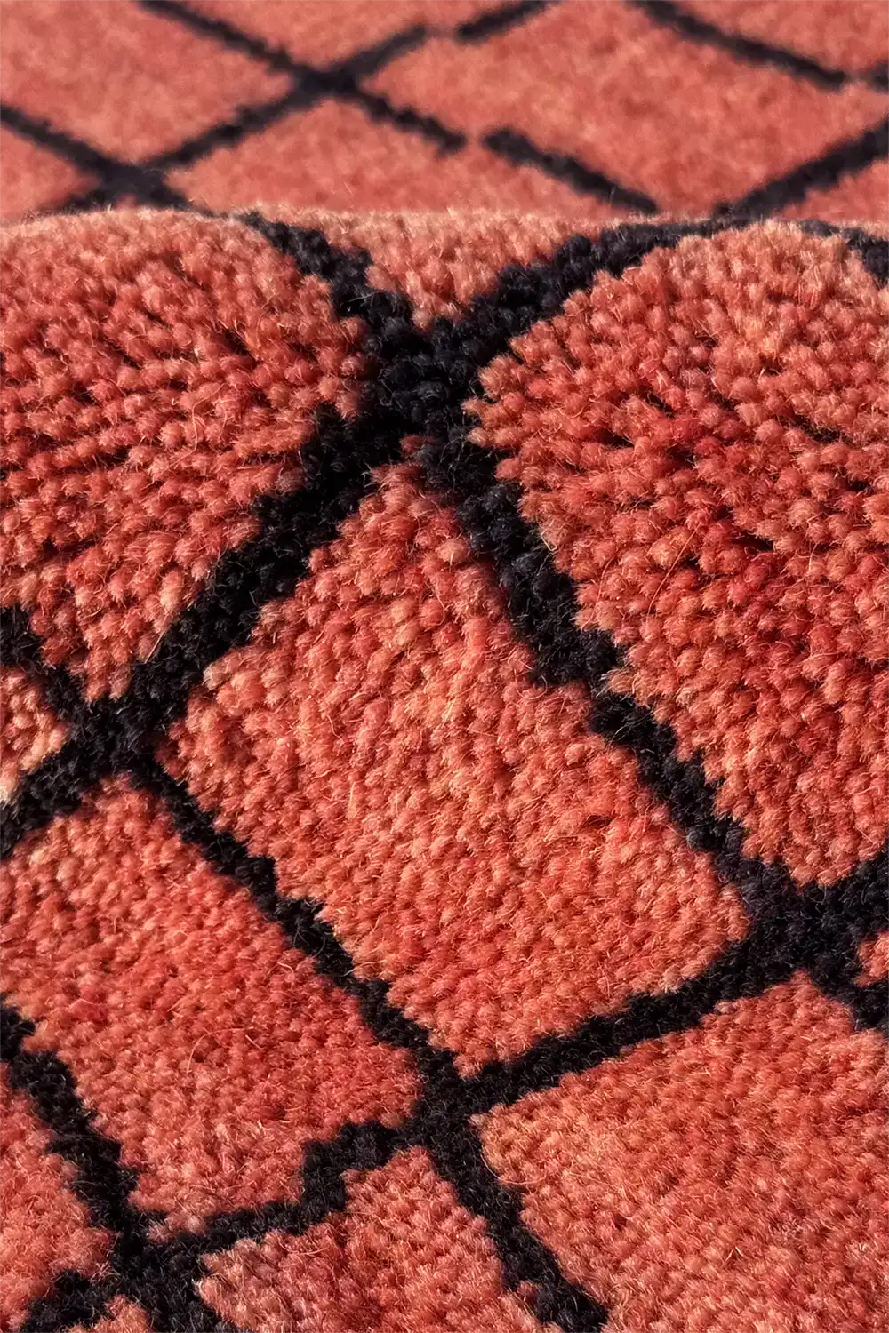 Close-up of a textured wool burnt rust orange rug with a grid pattern