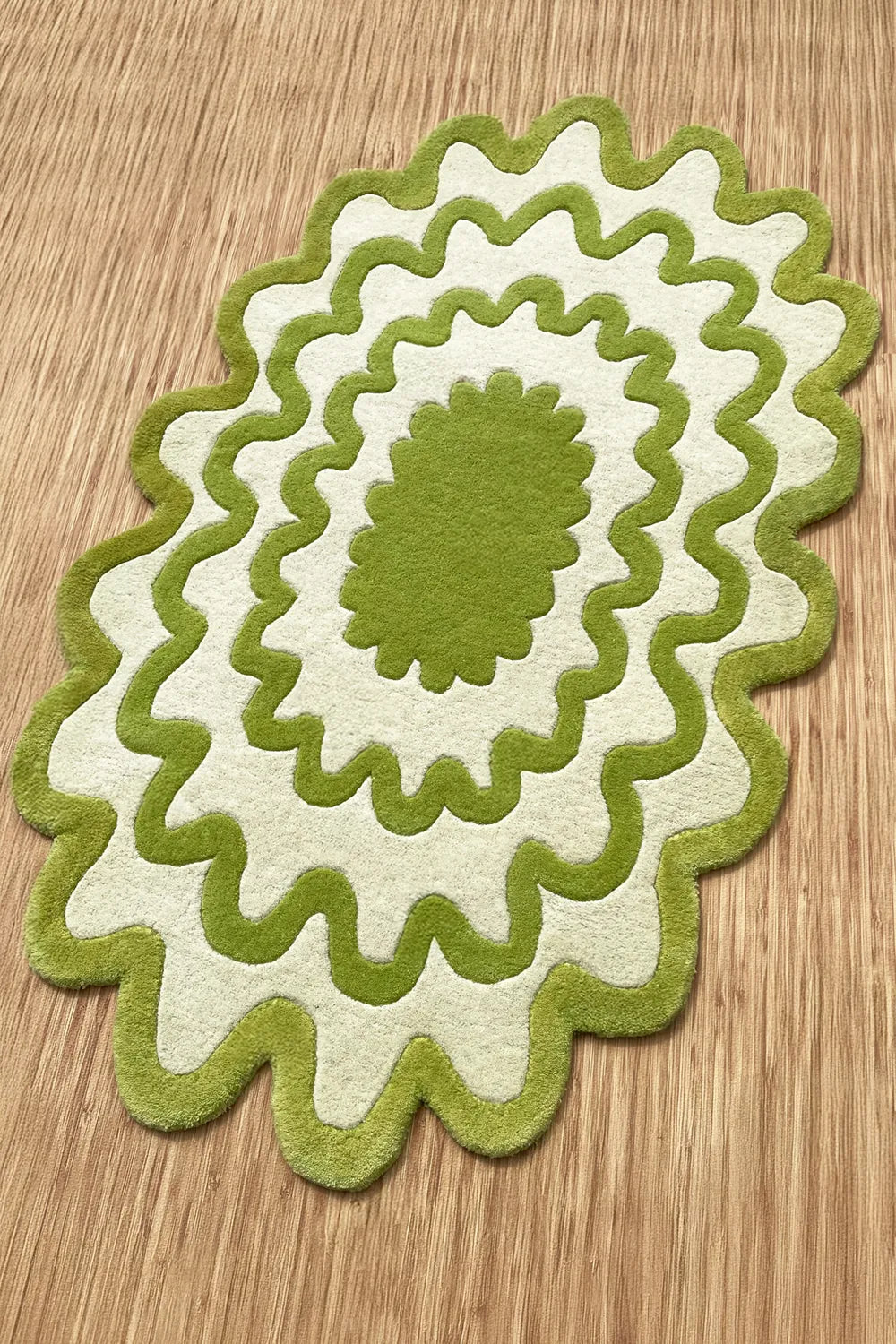 Hand-tufted wavy lime green rug with scalloped edges on a light wood floor, playful modern accent rug.