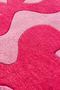 Close-up of a pink and red textured rug with abstract shapes.