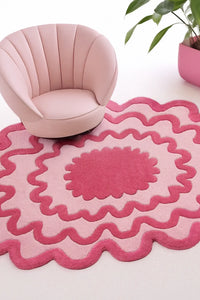 Pink modern accent chair on scalloped pink and red abstract area rug in contemporary funky living room lifestyle
