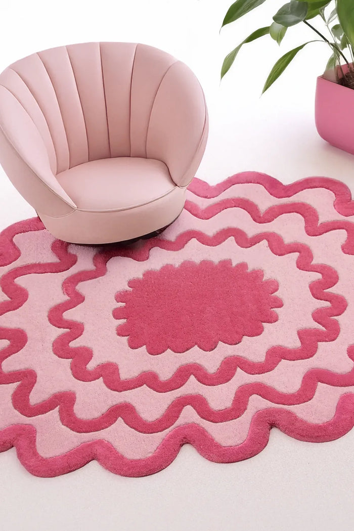 Pink modern accent chair on scalloped pink and red abstract area rug in contemporary funky living room lifestyle