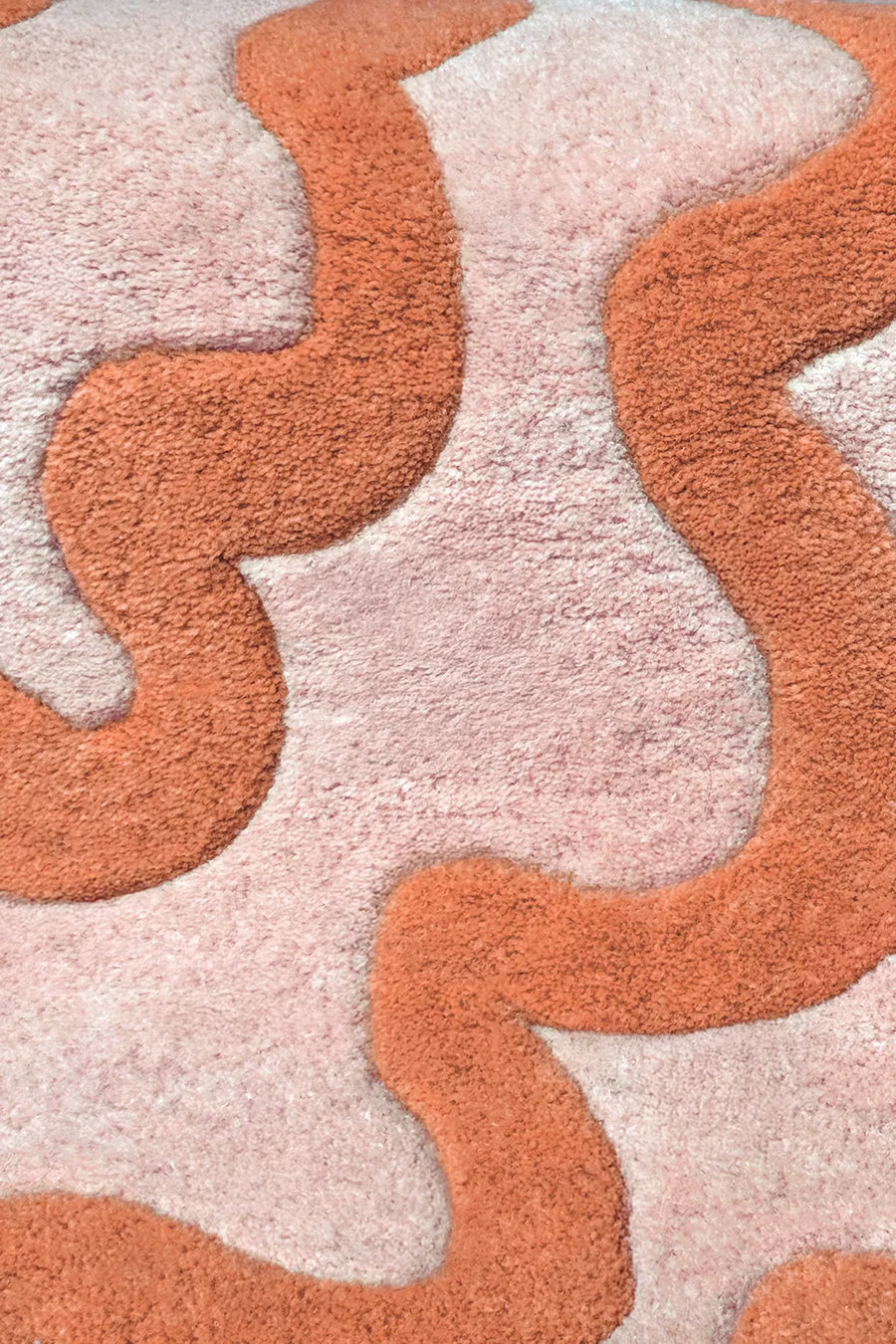 Close-up texture of orange and cream ripple wool rug, showing plush abstract design