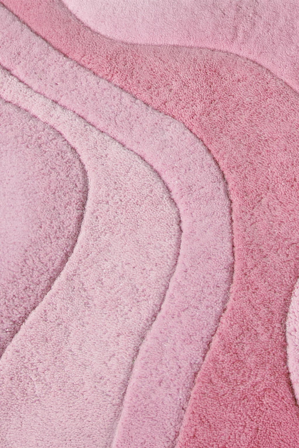 A close-up of a plush, textured pink rose rug with layered, wavy organic patterns in varying shades of light and medium pink.