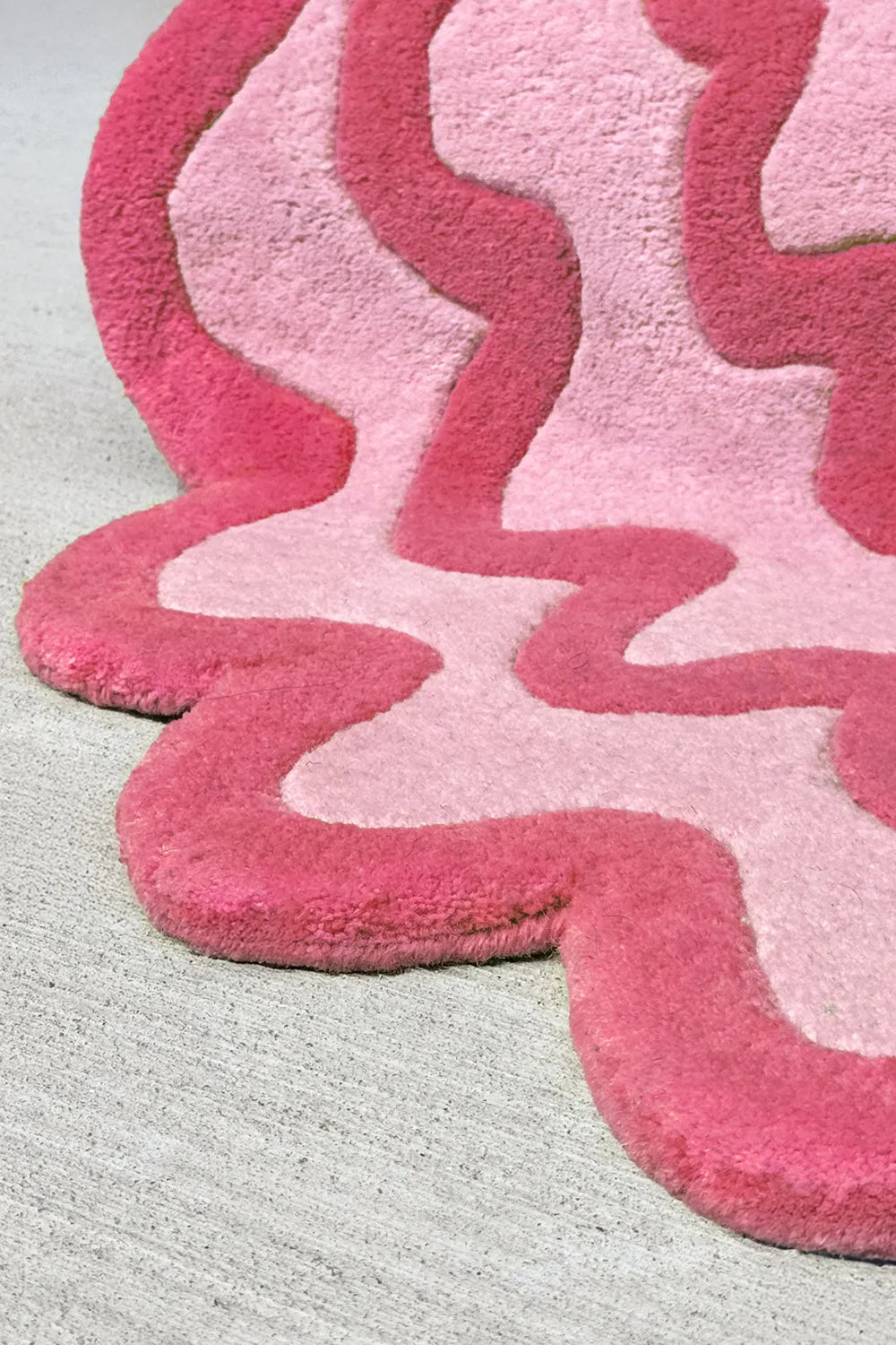 Close-up of textured pink and red modern wool rug with organic wave pattern