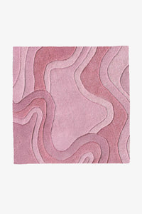 A square pink area rug with an abstract, layered wavy pattern in various shades of dusty rose and mauve, shown flat against a light gray background rose