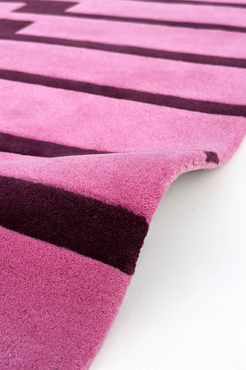 Close-up of a pink and purple striped square wool rug texture