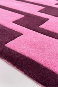 Close-up of a pink and purple geometric patterned wool rug.