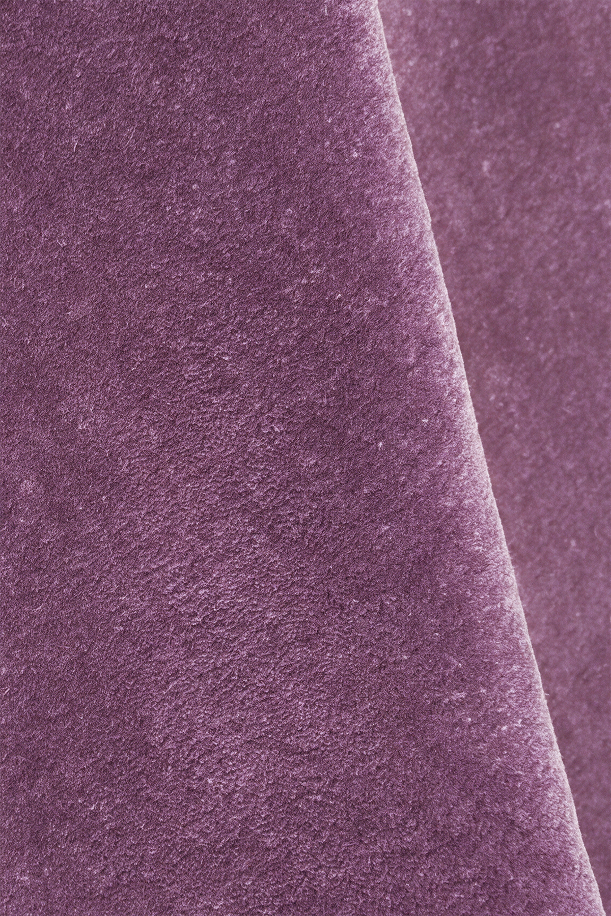 A close-up of textured mauve plum purple wool rug with a soft diagonal fold.