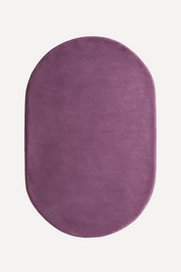 An oval-shaped plush rug in a dusty plum purple color, shown from a top-down view on a clean off-white background.
