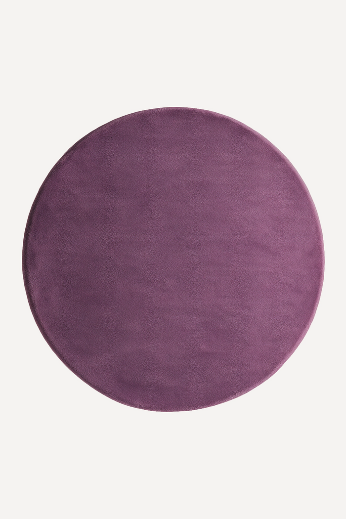 a plum purple round wool rug shown from above on a white background