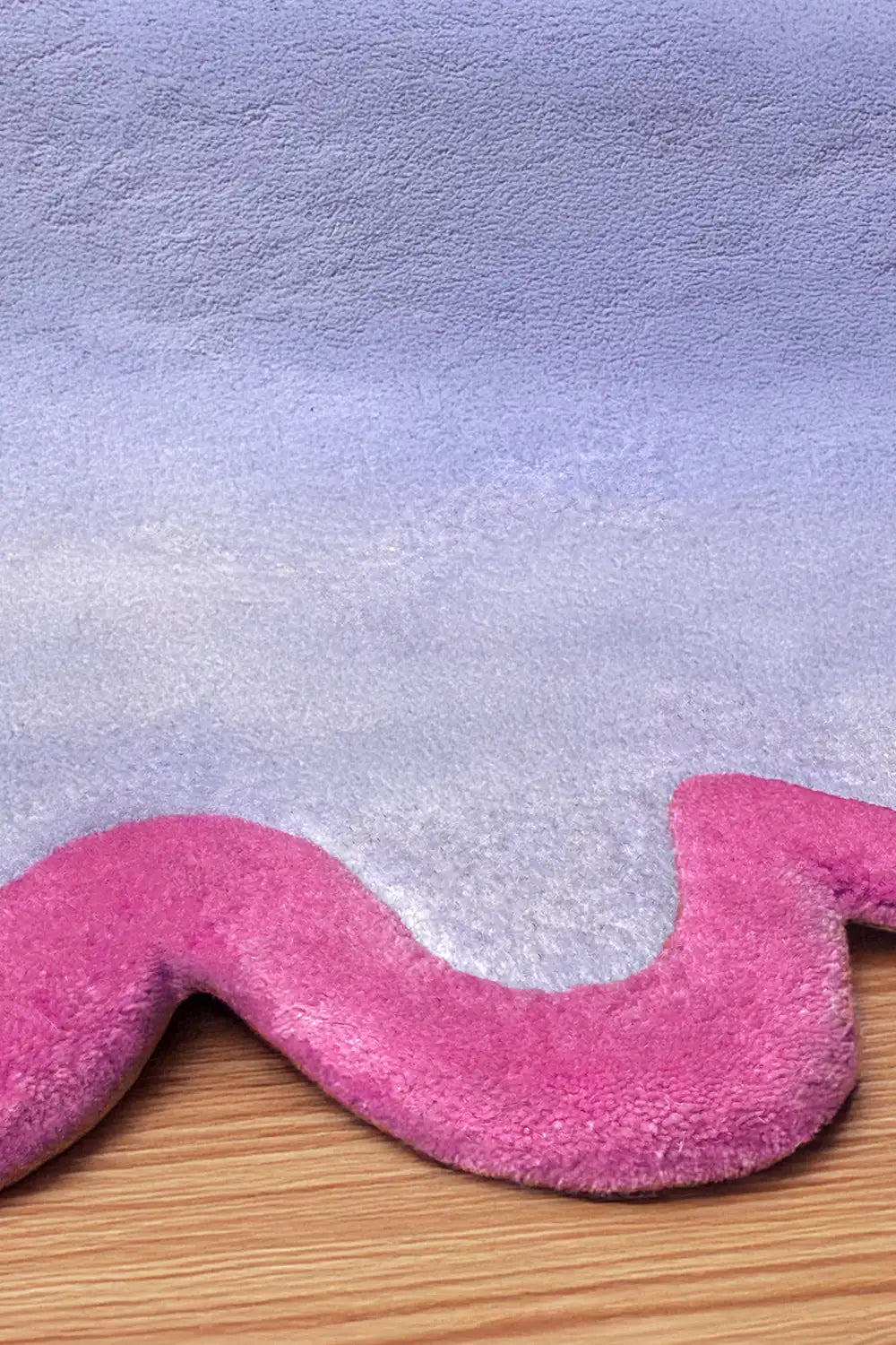 Detail of thick lavender and pink sculpted wool rug with curved squiggle border