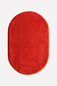 A vibrant red oval rug with a plush, soft texture, shown from a top-down view on a light gray background.