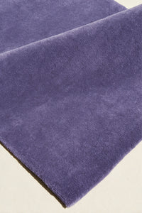 close up texture of a purple cornflower hand-tufted wool rug folded over to show its soft cut pile