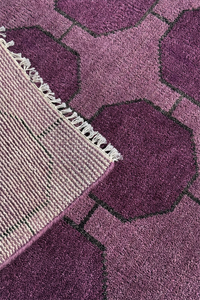 Close-up of a purple geometric patterned rug with a white fringe edge