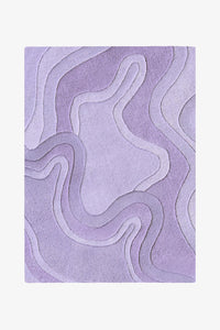 A rectangular area rug with an abstract, layered topographic design in shades of lavender and light purple, shown flat against a light off-white background.