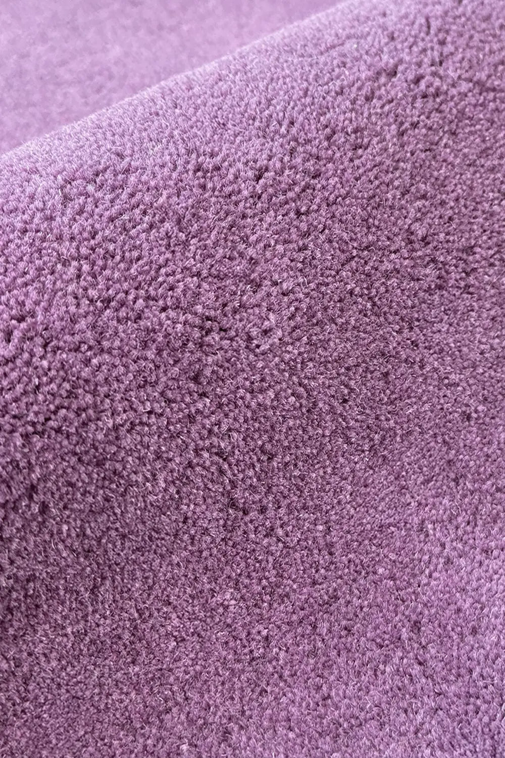 Solid purple wool rug texture close-up, soft modern area rug for bedroom or nursery
