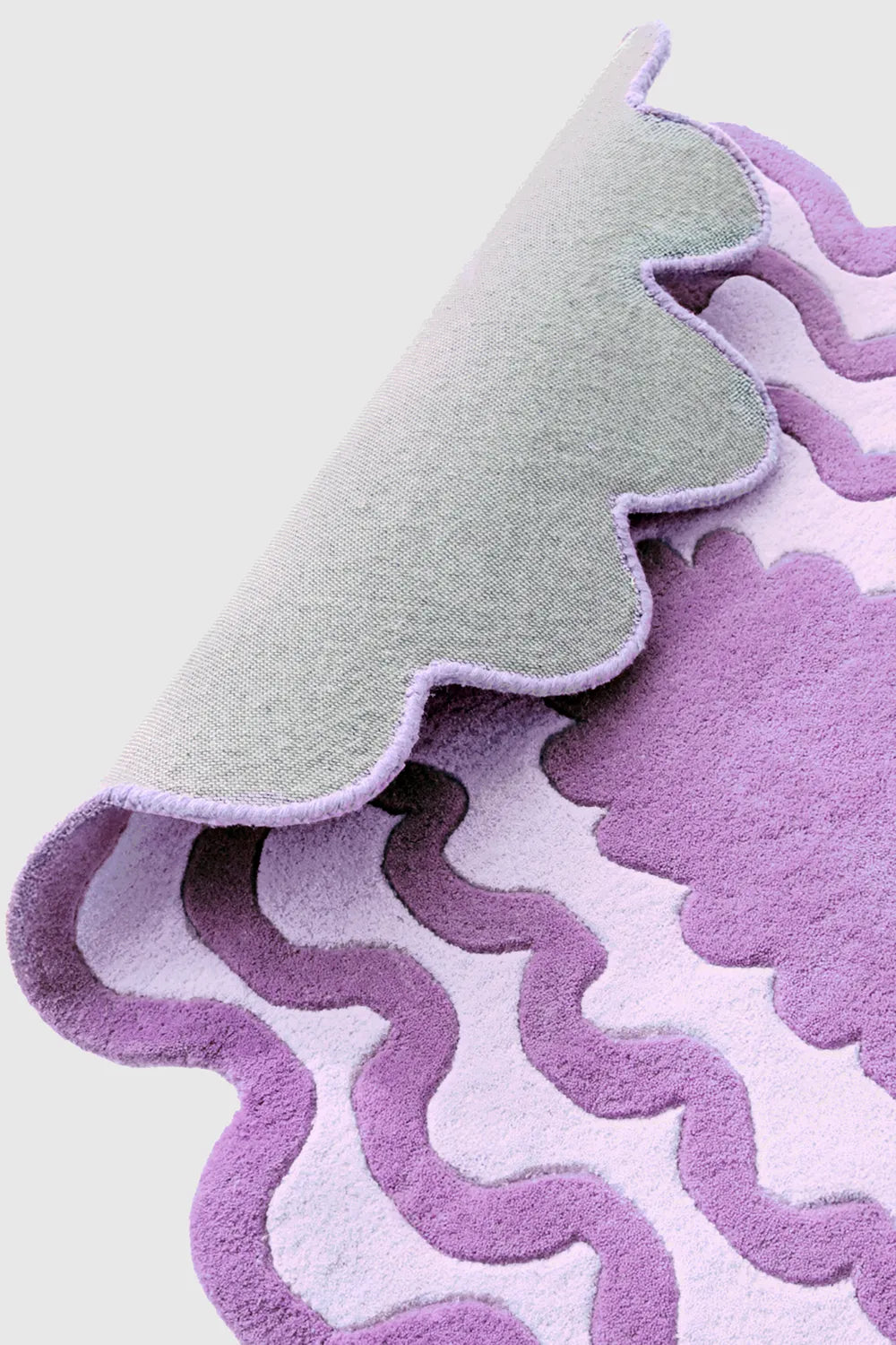Back side of purple scalloped wool rug showing hand-tufted texture and wavy modern design.
