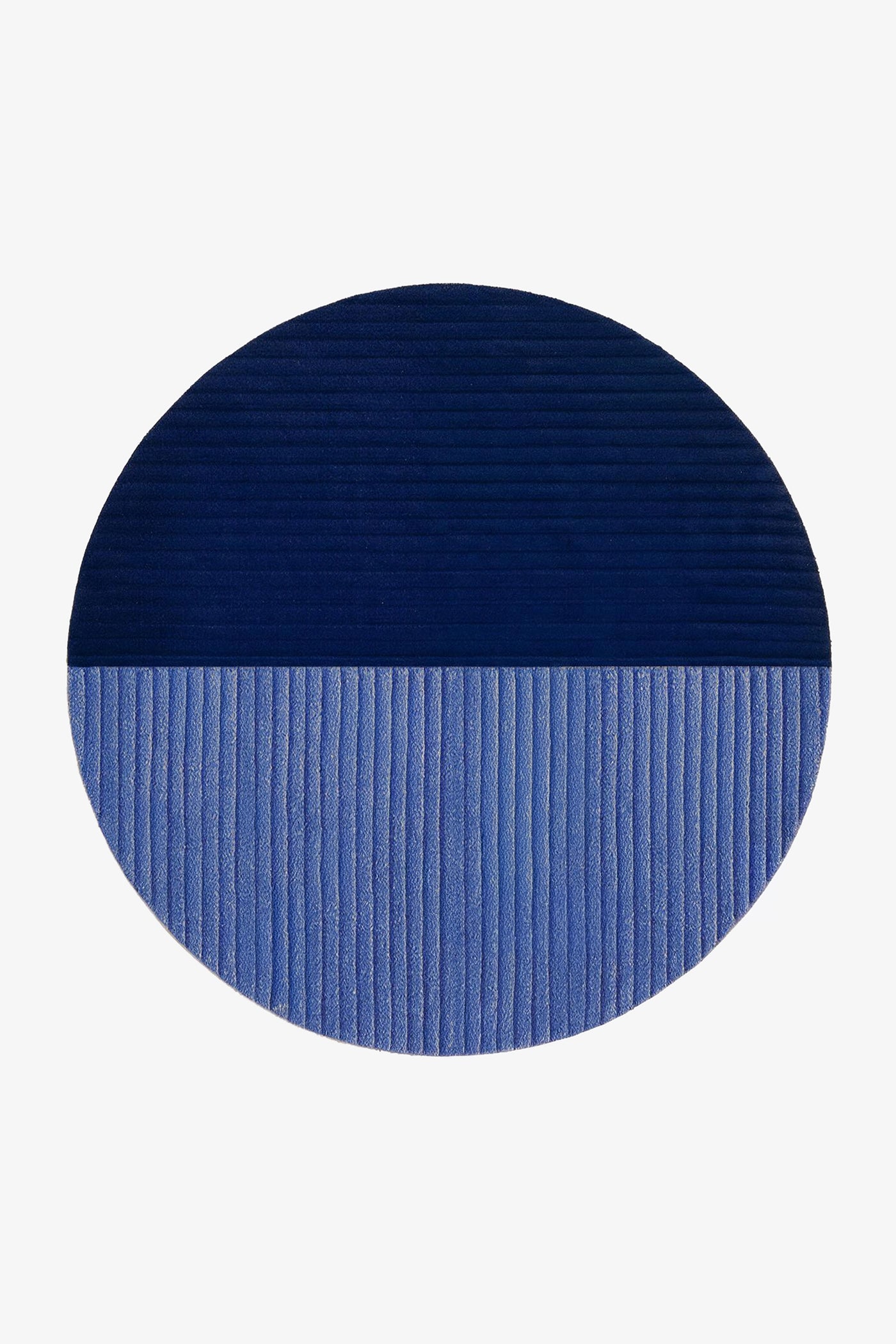 A round area rug with a split color-block design, featuring a dark navy blue top half and a medium blue bottom half, both with a ribbed texture, shown on a plain white background.