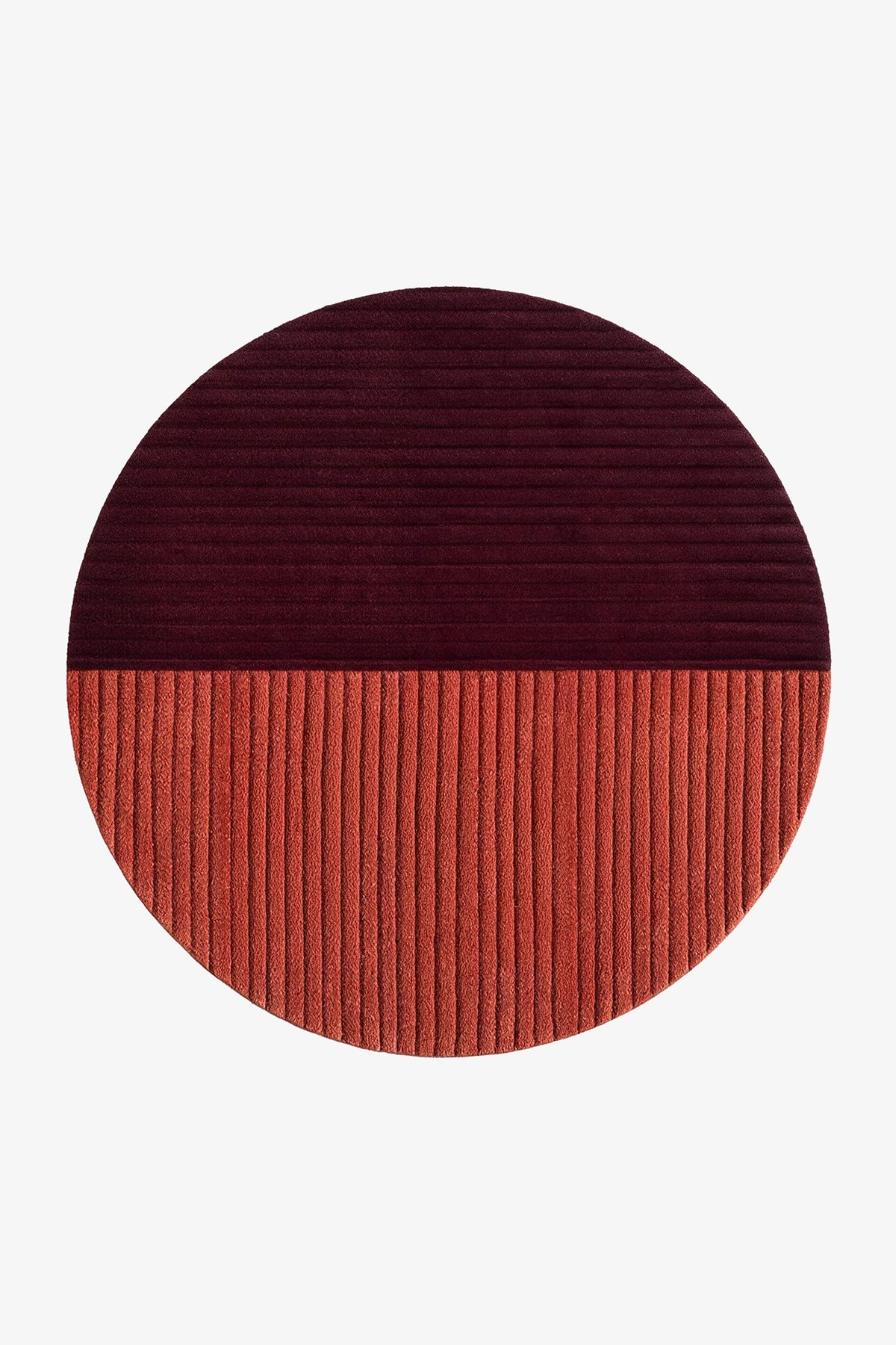 A round ribbed rug split horizontally into two colors: a dark burgundy top half and a terracotta orange bottom half, shown on a plain white background rust