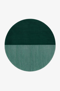 A round area rug with a split design, featuring a dark forest green top half with horizontal ribbing and a muted teal-green bottom half with vertical ribbing, shown on a plain white background.