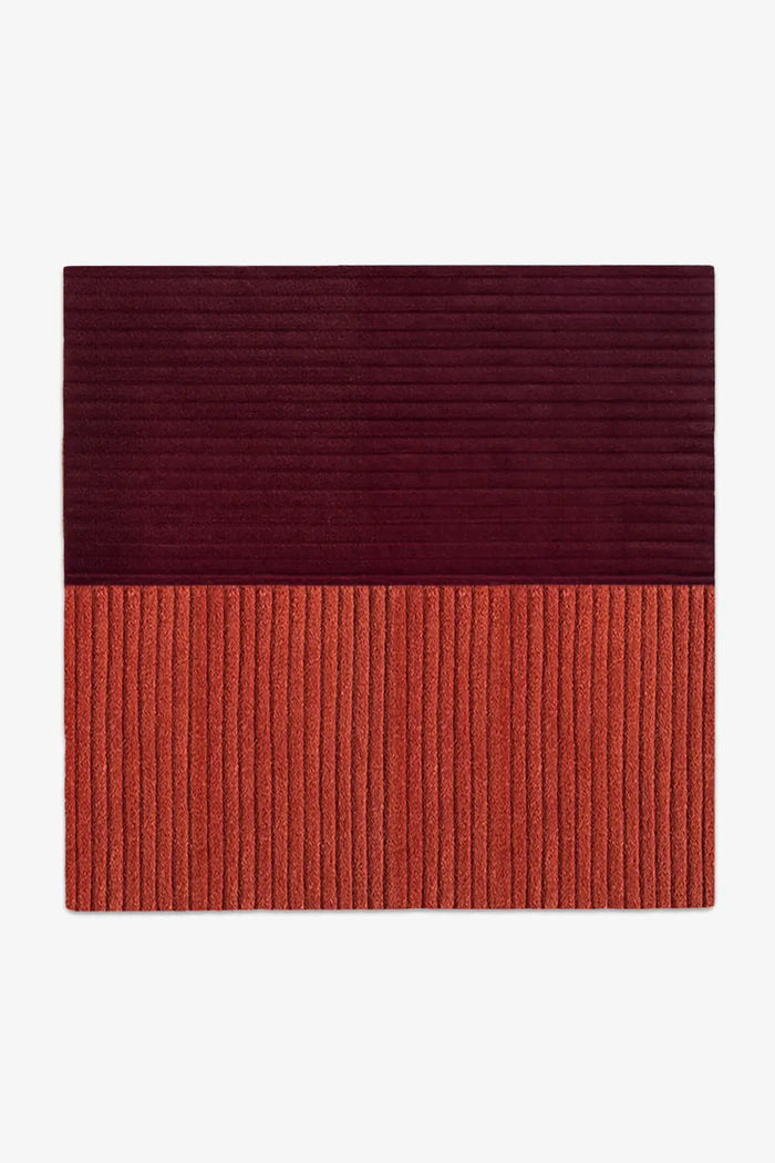Two-tone red and bunt orange square rug with a ribbed texture on a white background
