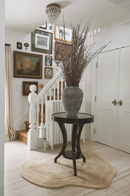 wavy beige textured rug on a light wooden floor with a wooden table corner.