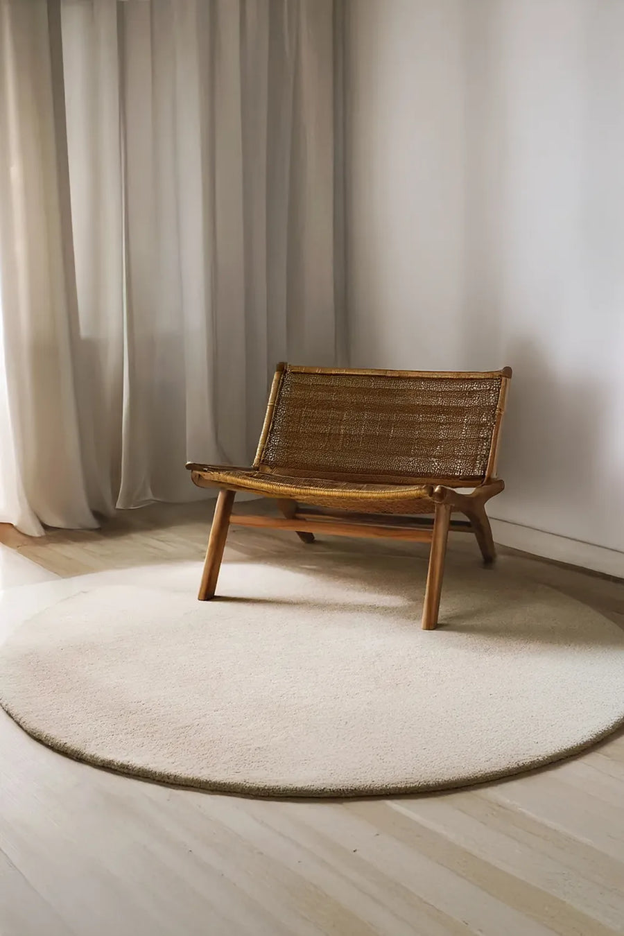 Natural cream round wool rug styled under mid-century woven chair, perfect for 6ft or 8ft round sizing