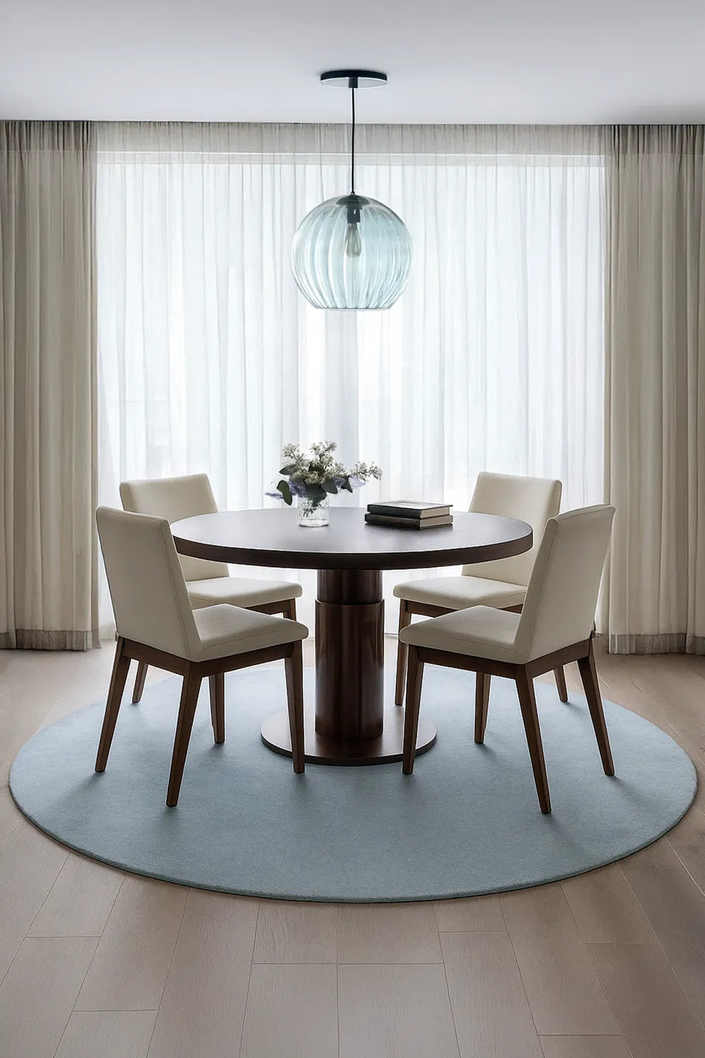 Modern 8ft round blue rug styled under a round dining table in bright minimalist dining room