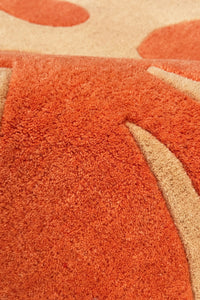 Close-up of a textured orange and beige runner rug with abstract patterns.