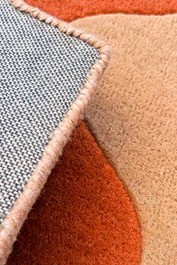 Close-up of a textured square rug with geometric pattern in various colors.