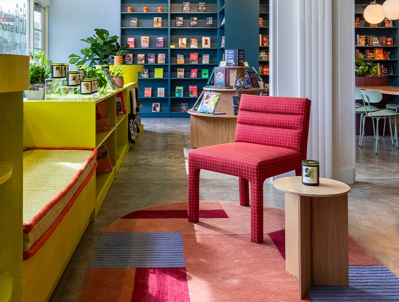 Modern interior design with a red chair, colorful rug, and bookshelves.
