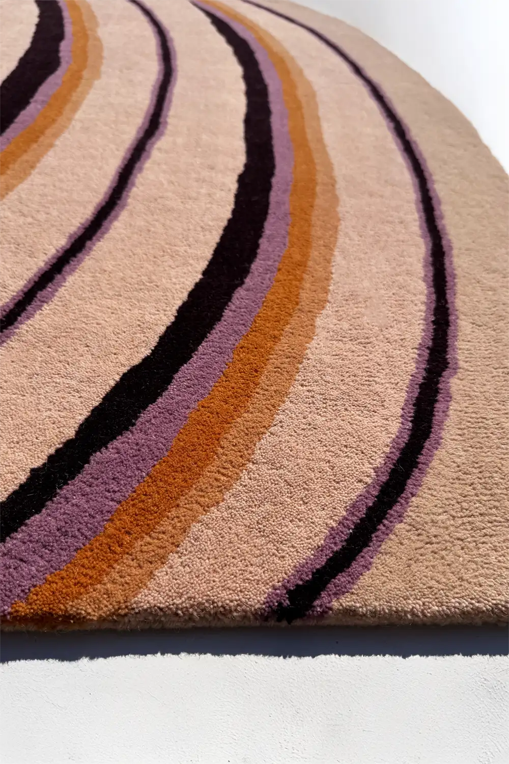 Rug with wavy pattern in purple, orange, and black on a white background