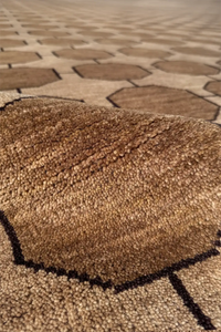 Close-up of a textured light taupe and beige wool rug with geometric pattern 
