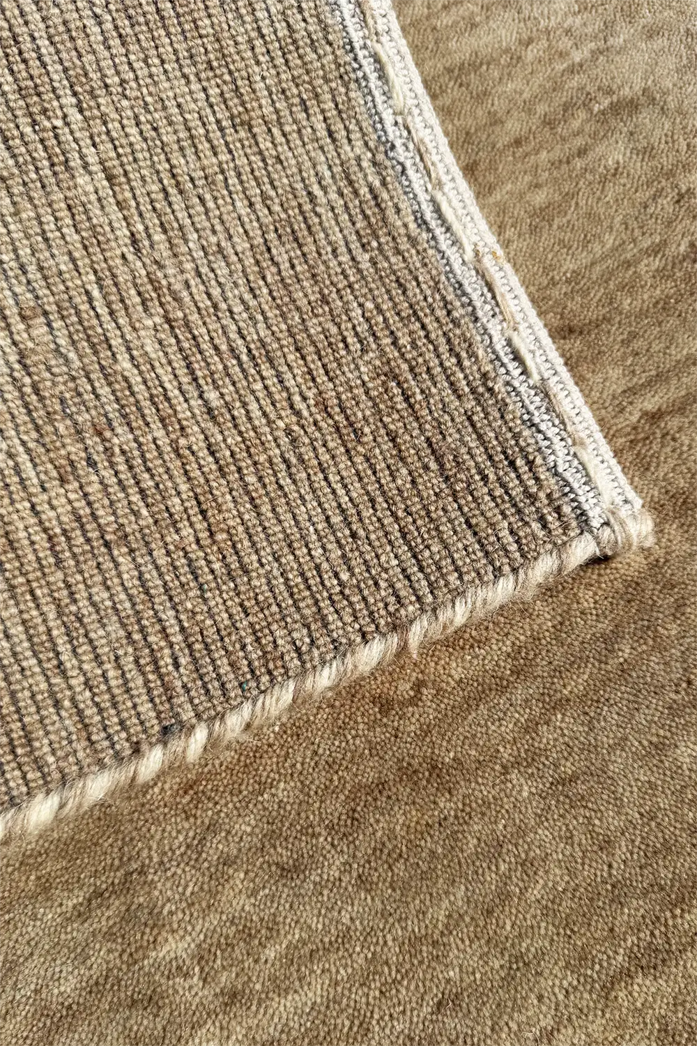 Close-up of a textured beige carpet corner hand-loomed in wool