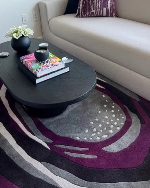 Round coffee table with decorative items on a patterned rug in a living room.