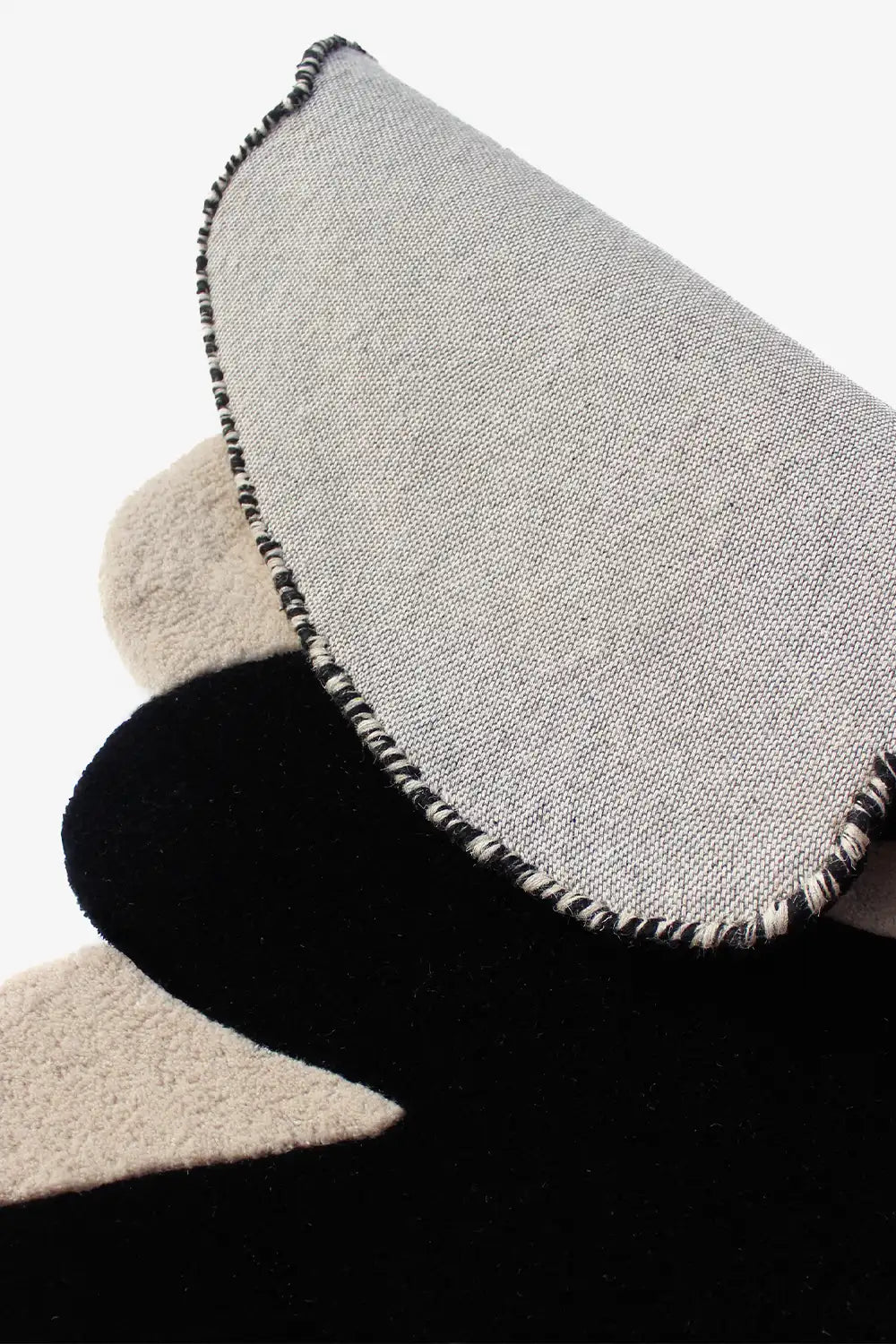 Close-up of underside and edges of sculptural ivory and black rug