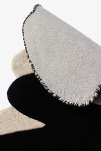 Close-up of underside and edges of sculptural ivory and black rug