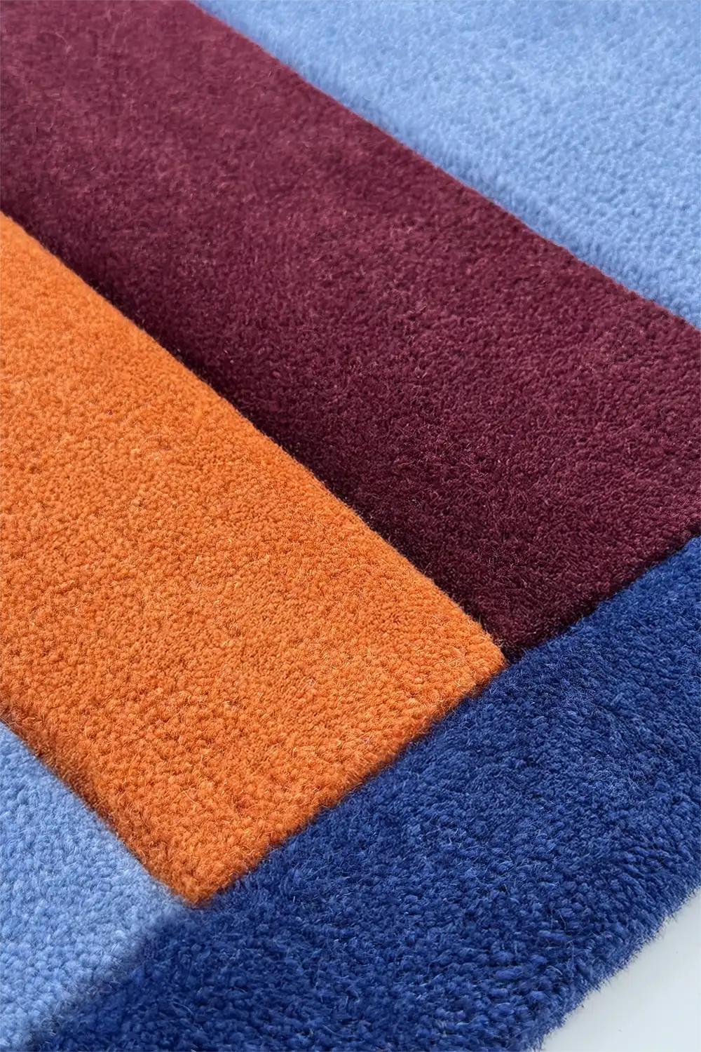 Colorful square wool rug in red, orange, and blue.