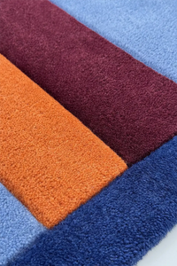 Colorful square wool rug in red, orange, and blue.