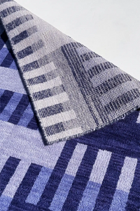 Textured wool area rug with blue and gray pattern on a white background lifestyle