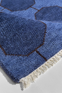 Blue knotted runner rug with geometric pattern on a light gray background