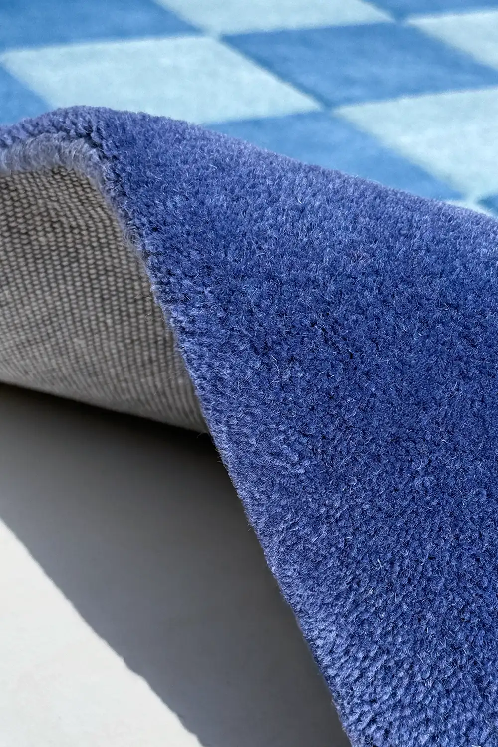 Close-up of a blue textured rug with a checkered pattern in the background